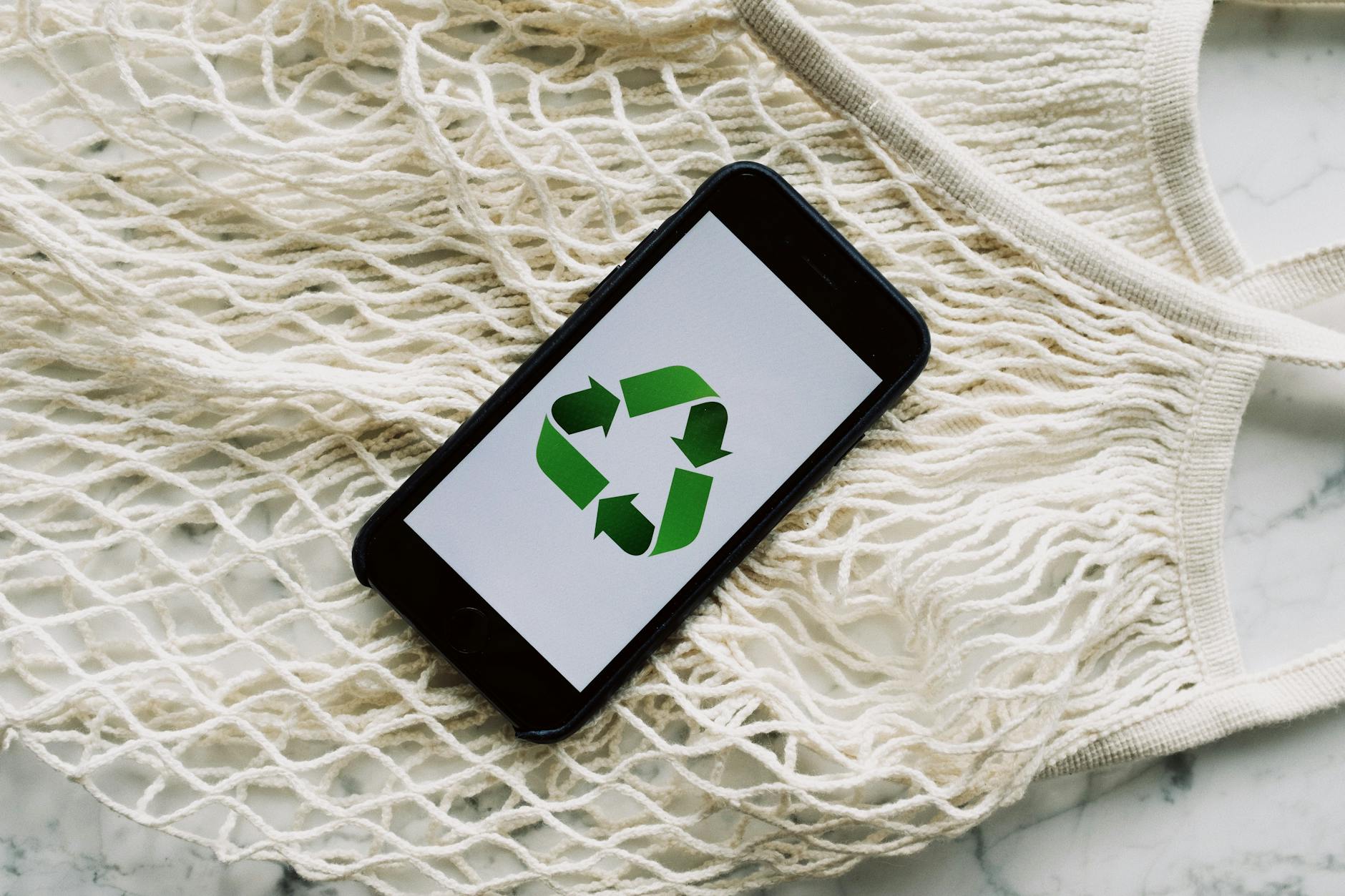 smartphone with green recycle symbol and mesh bag